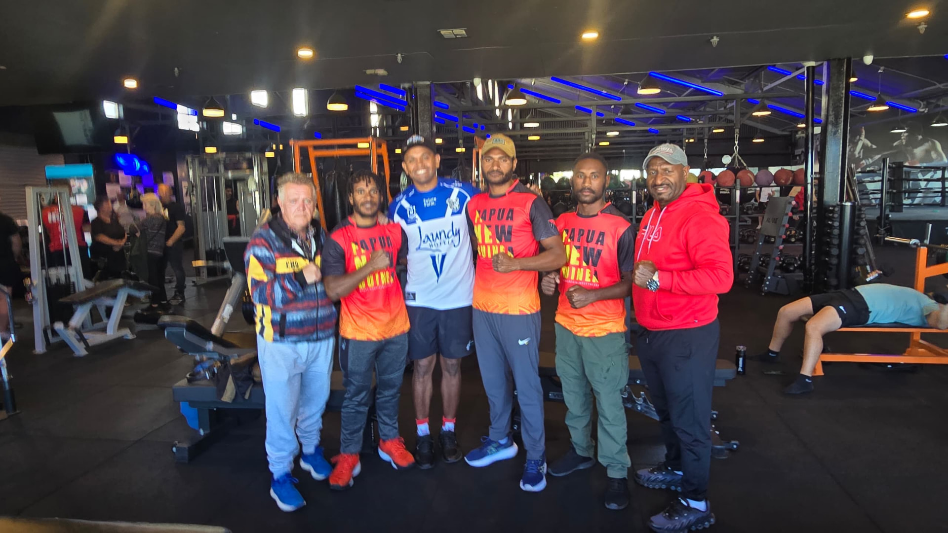 PNG fighters and coaches with international trainers inside a gym before fight week